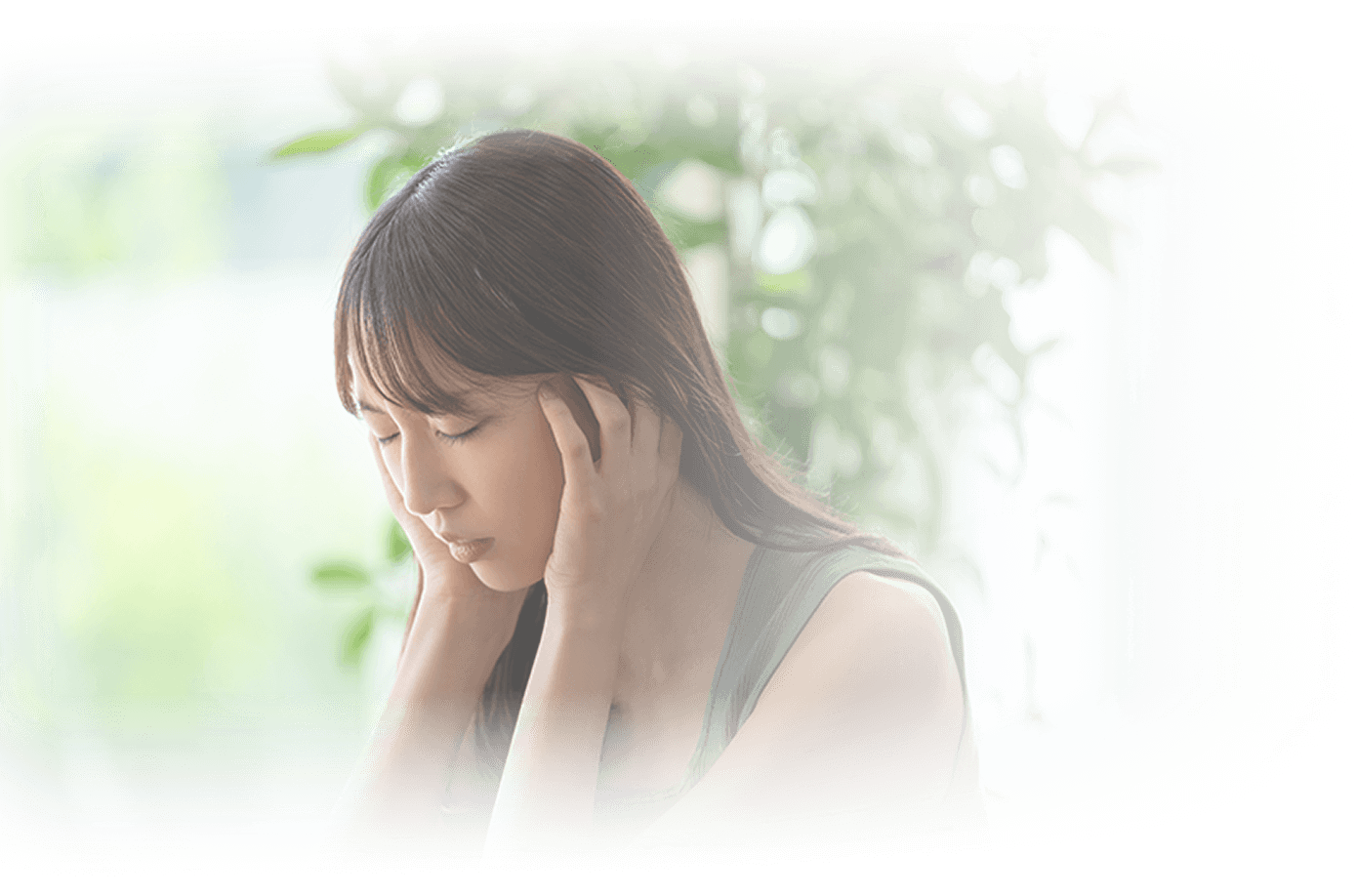 側頭部を手でおおい、困っている表情の若い女性